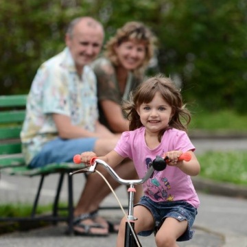 Dítě na kole s babičkou a dědou v parku
Radost z první jízdy, přírodní světlo